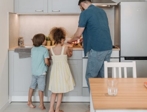 Father and children cooking together in a modern kitchen, enjoying family time.